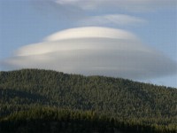 Lenticular clouds are caused by a wave wind pattern created by the mountains. They look like discs or flying saucers that form near mountains.